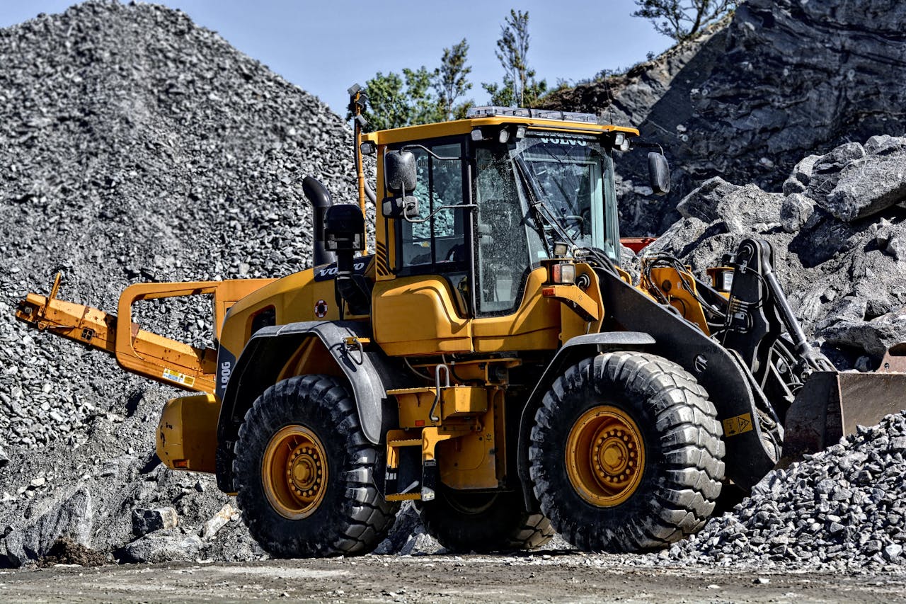 Powerful yellow construction loader moving gravel in an industrial quarry site.