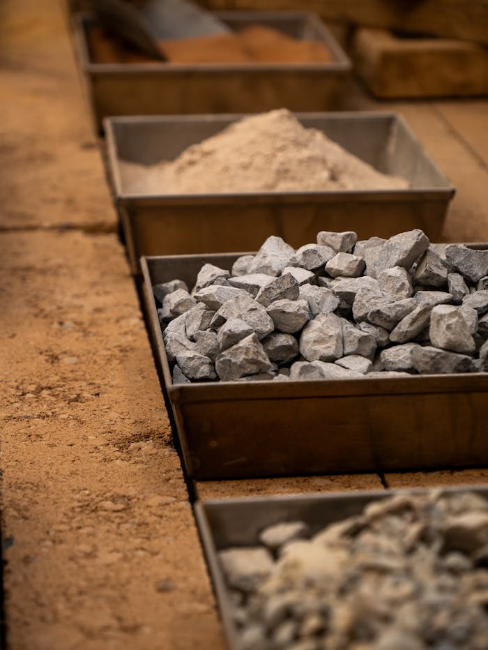 Various construction materials including rocks, and sand in storage boxes.